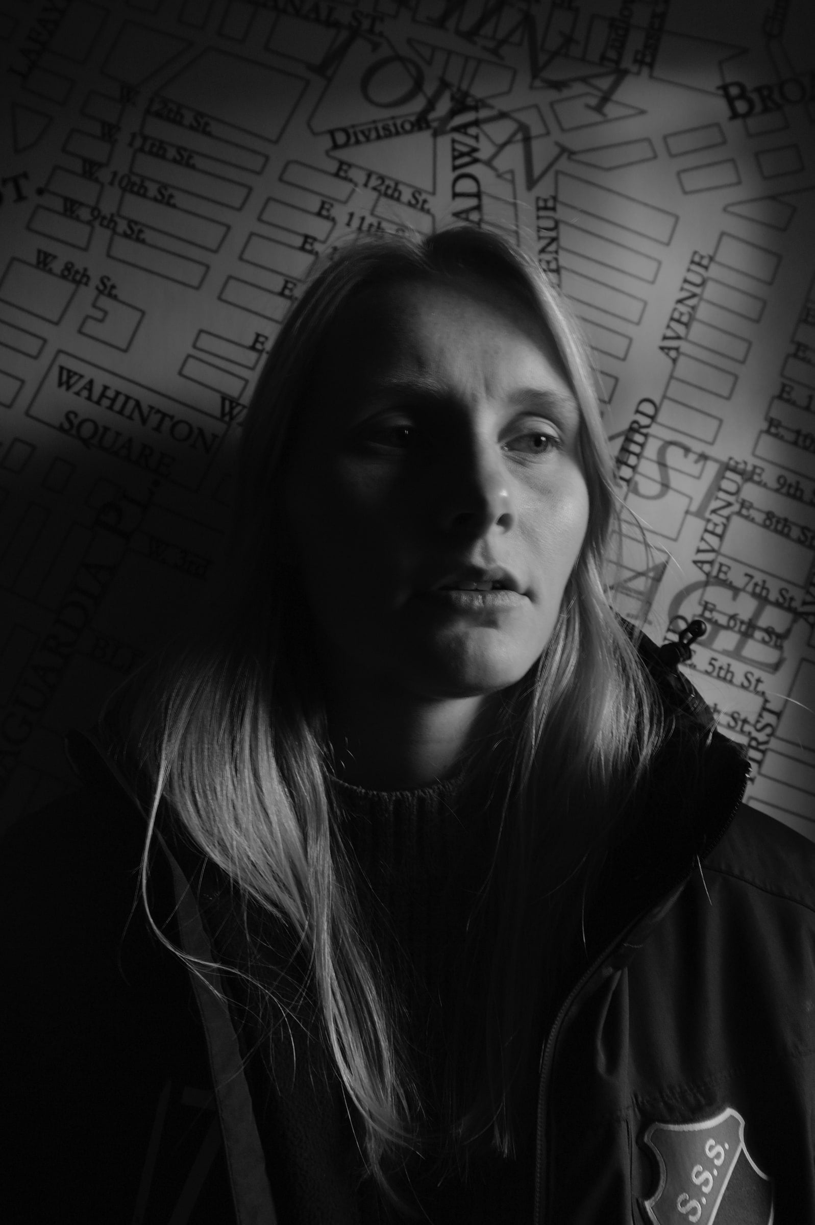 Zwart-witportret van een vrouw met lang blond haar in een donkere jas, met een geprojecteerde stadsplattegrond over haar gezicht en de achtergrond (cover)